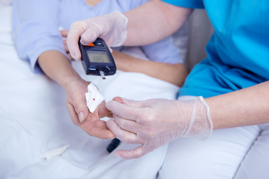 Patient receives blood glucose test in hospital bed from doctor
