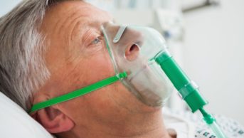 A man in a hospital bed wearing an oxygen mask