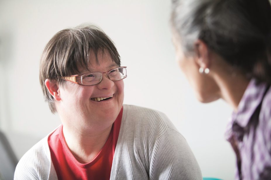 How to overcome barriers to effective consultation with adults with learning disabilities and practical ways to improve pharmacy consultation skills. In the image, an adult with Down’s syndrome speaks with a consultant