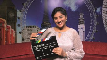 Bav Heer, pharmacist and television presenter holds a clapperboard