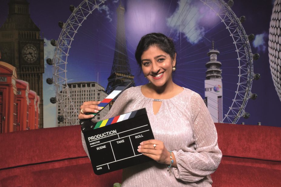 Bav Heer, pharmacist and television presenter holds a clapperboard