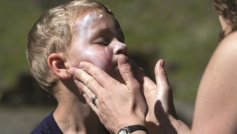Woman applies sunscreen on a toddler's face