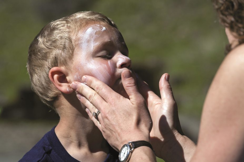 Woman applies sunscreen on a toddler's face