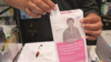Pharmacist giving out medication in cancer awareness paper bag