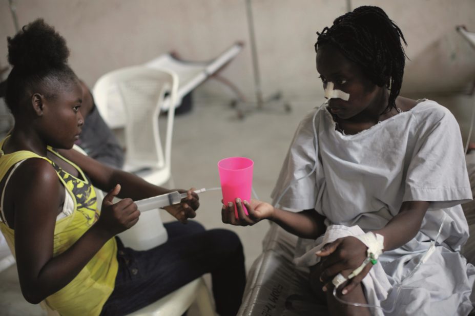 A relative drip-feeding a patient in the Cholera Treatment Centre in Haiti