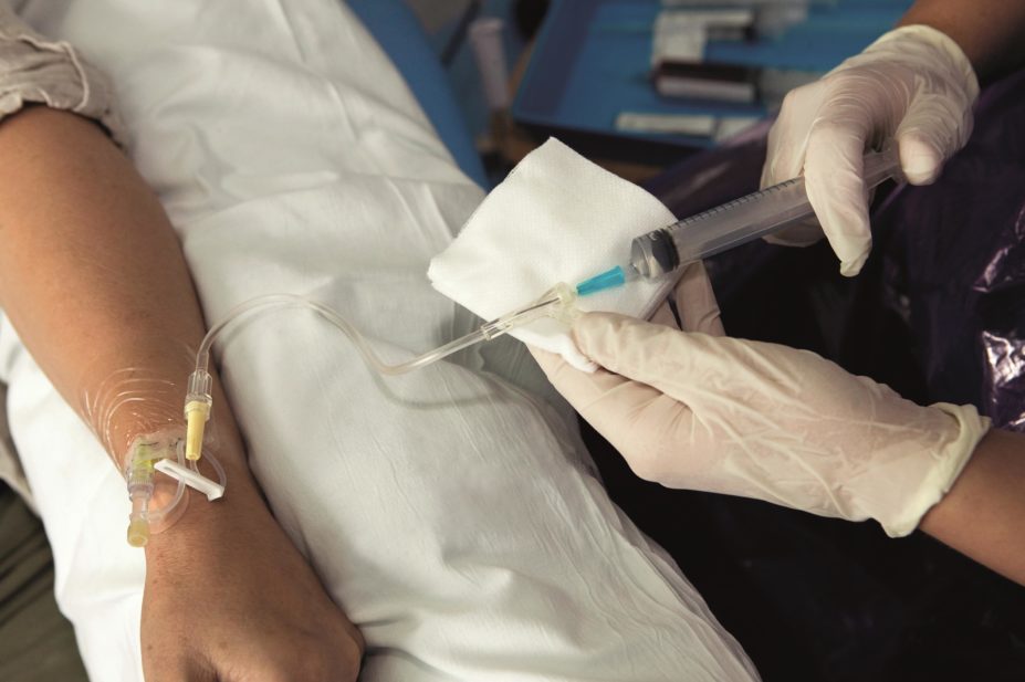 Close up of a nurse injecting a chemotherapy drug intravenously through a patient's arm