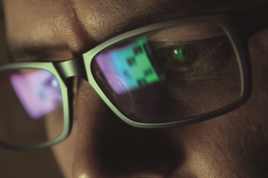 Close up of computer screen reflected on a man's eyeglasses