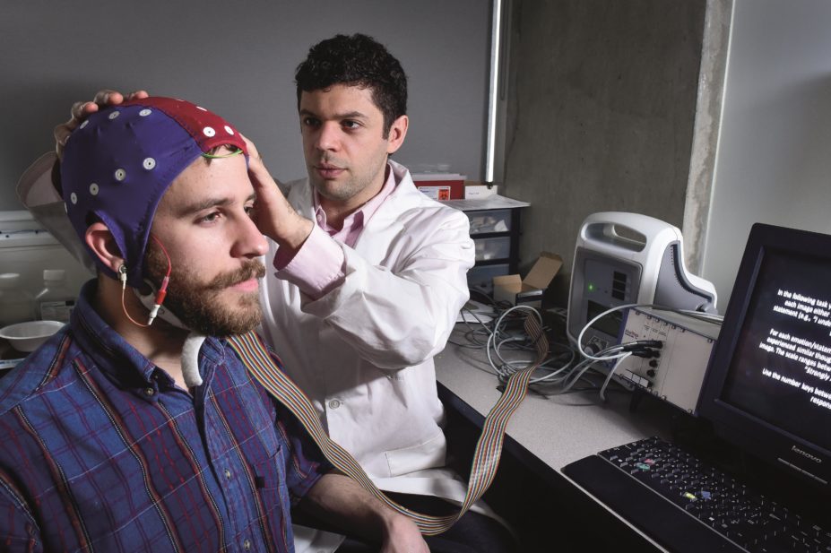 Daniel Randles, author of the research, sets up a participant to the EEG equipment used for the study