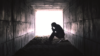 Man clutching head in dark tunnel, depression concept