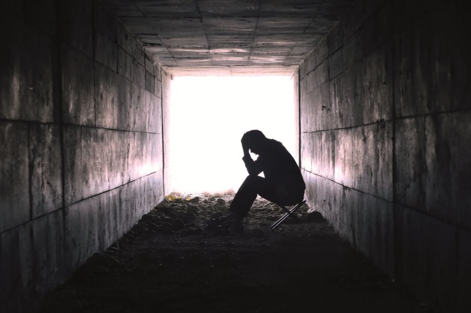 Man clutching head in dark tunnel, depression concept