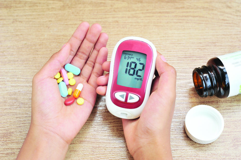 hand holding diabetes drugs and glucometer