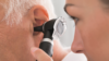 A doctor checks an elderly patient's ear