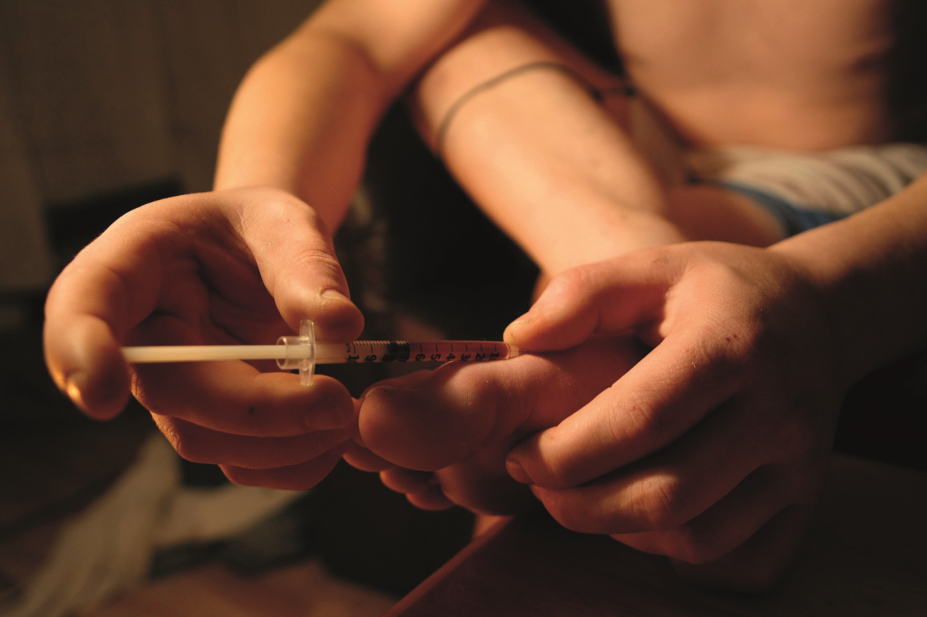 Drug user injecting heroin in foot