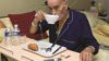 Elderly person eating with medicines on the table