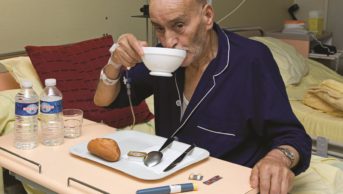 Elderly person eating with medicines on the table