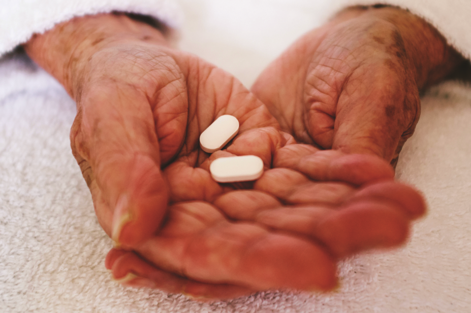 Close up of elderly person's hands holding pills