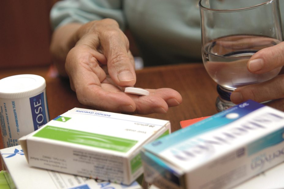 Around 50% of GPs are not confident that their elderly patients are taking their medicines correctly three months after their last consultation, according to a survey by Pharmacy Voice. In the image, an elderly woman holds a pill and a glass of water