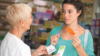 Young woman talks to pharmacist while holding emergency hormonal contraception blisters