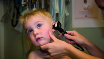 Close up of a health worker examining a toddler's ear