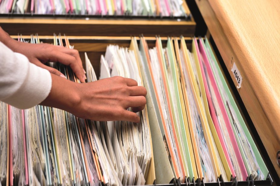 Tools and guidance to help pharmacists record and review near miss errors to reduce the chance of future mistakes have been published by the Royal Pharmaceutical Society (RPS). In the image, a person going through files