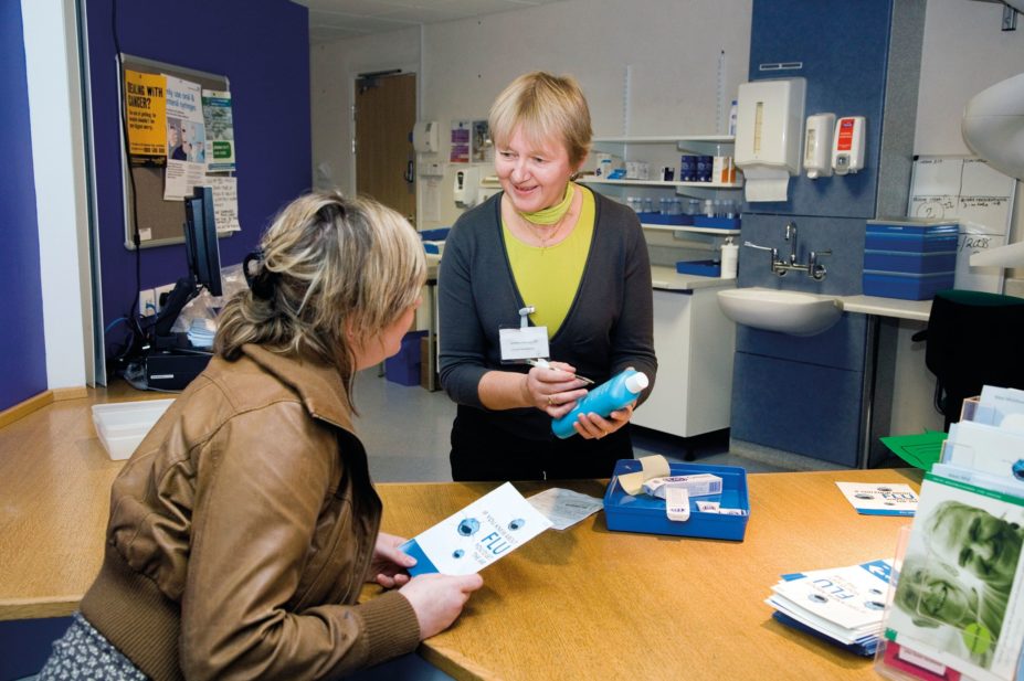 Patient (left) collecting and discussing her prescription with a pharmacist at the outpatients pharmacy of a hospital