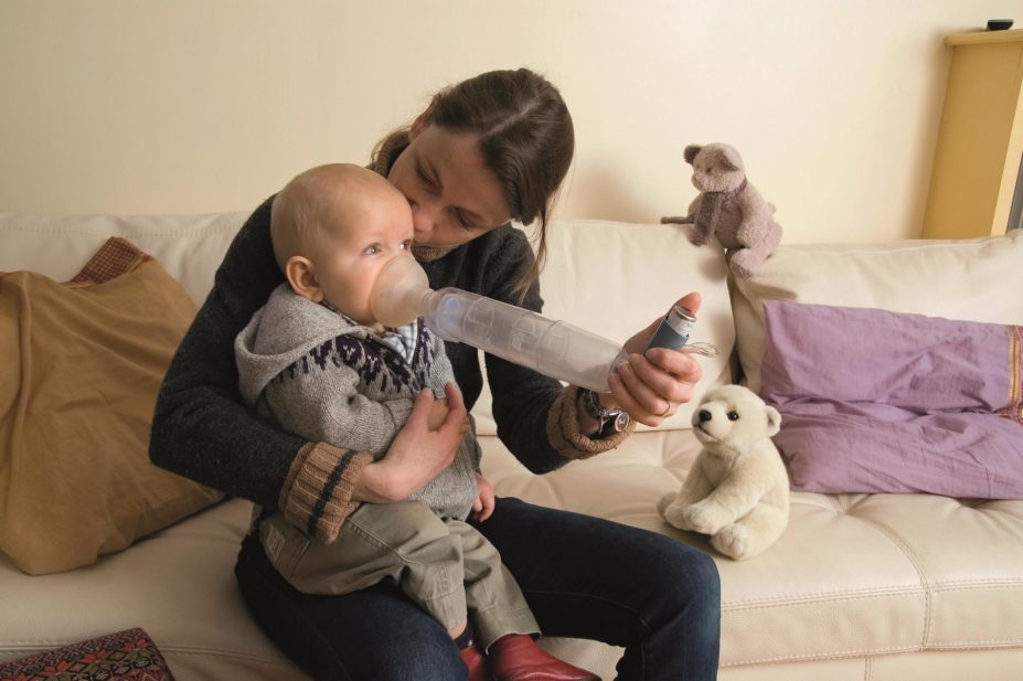 Infants who use inhaled corticosteroids during the first two years of life are relatively short for their age. In the image, mother helps her child use an inhaler