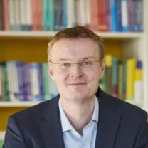 James sits in front of a bookshelf