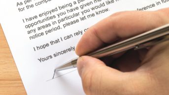 Close up of person signing a resignation letter