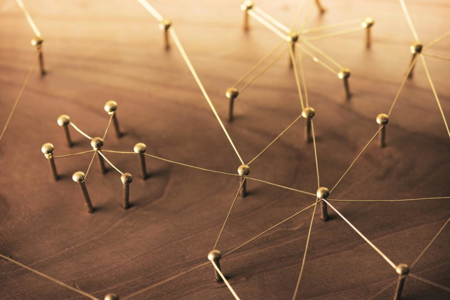 Abstract image of interconnecting networks made of gold wires linking golden pegs on rustic wood
