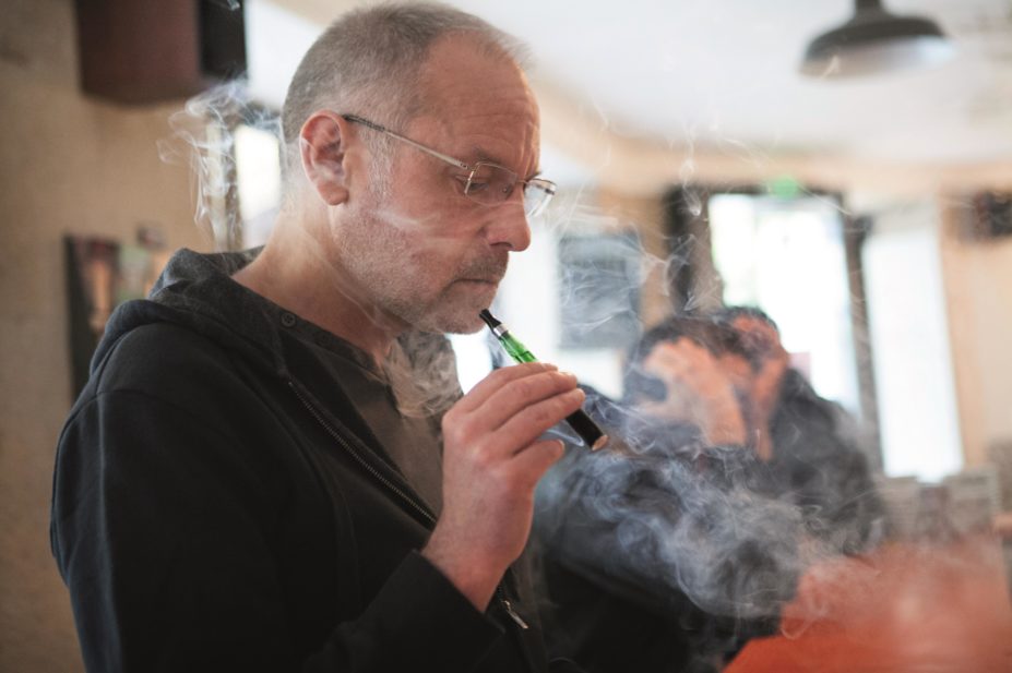 Man smoking e-cigarette, which is not a reliable smoking cessation aid, according to cancer research
