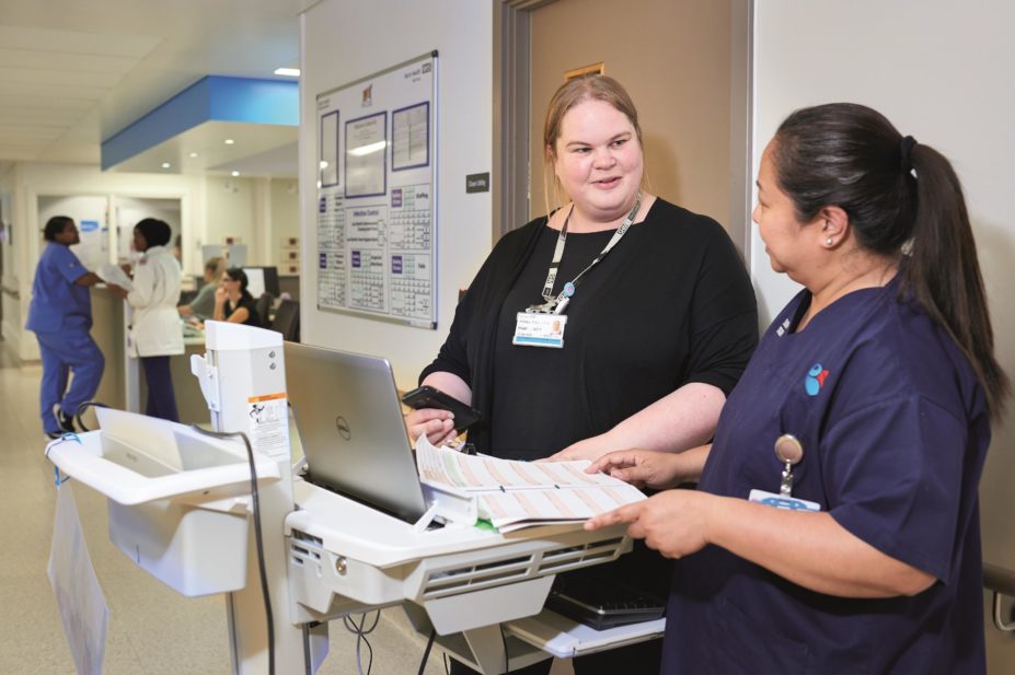 Michelle Sullivan, pharmacy technician at Barts Health NHS Trust in London, speaks with one of the hospital staff
