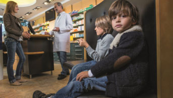 Mother speaking to pharmacist and child looks at camera