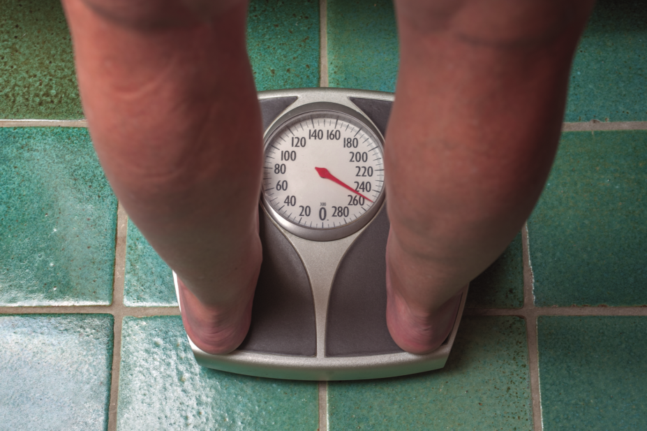 Overweight person standing on weighing scales