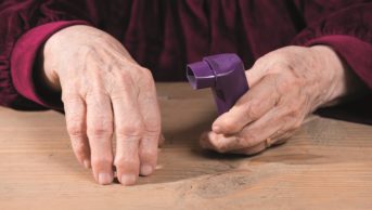 An older person's hands with an inhaler