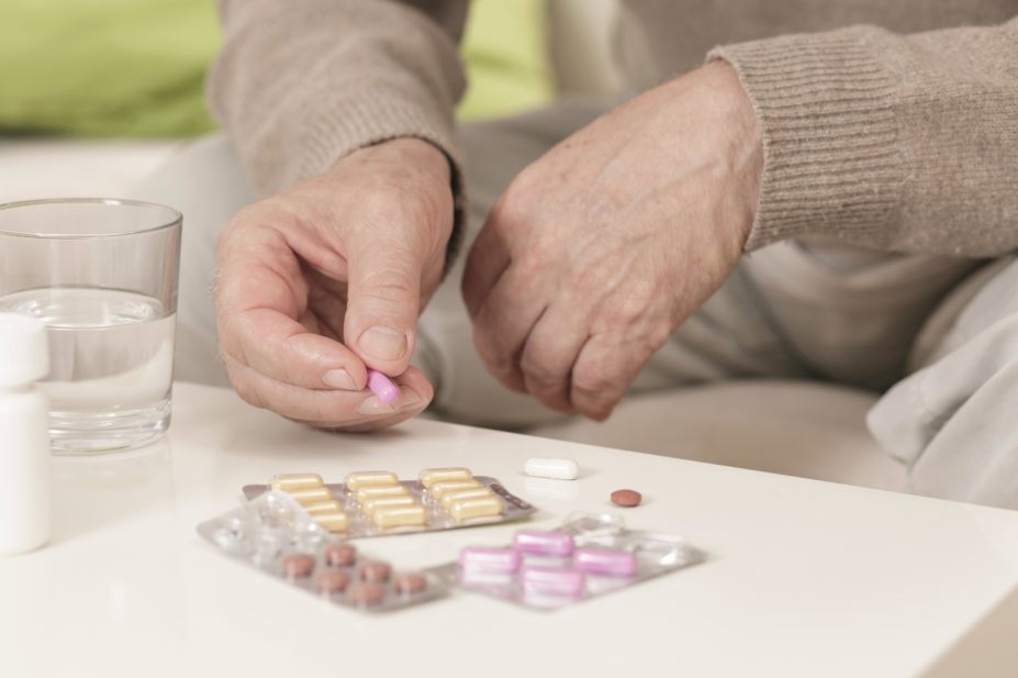 Older person with a range of medicines in blister packs on the table