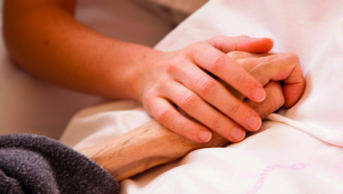 Close up of young woman holding elderly patient's hand