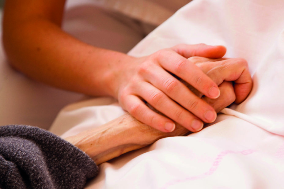 Close up of young woman holding elderly patient's hand