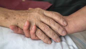 Health worker holding a dying patient's hand