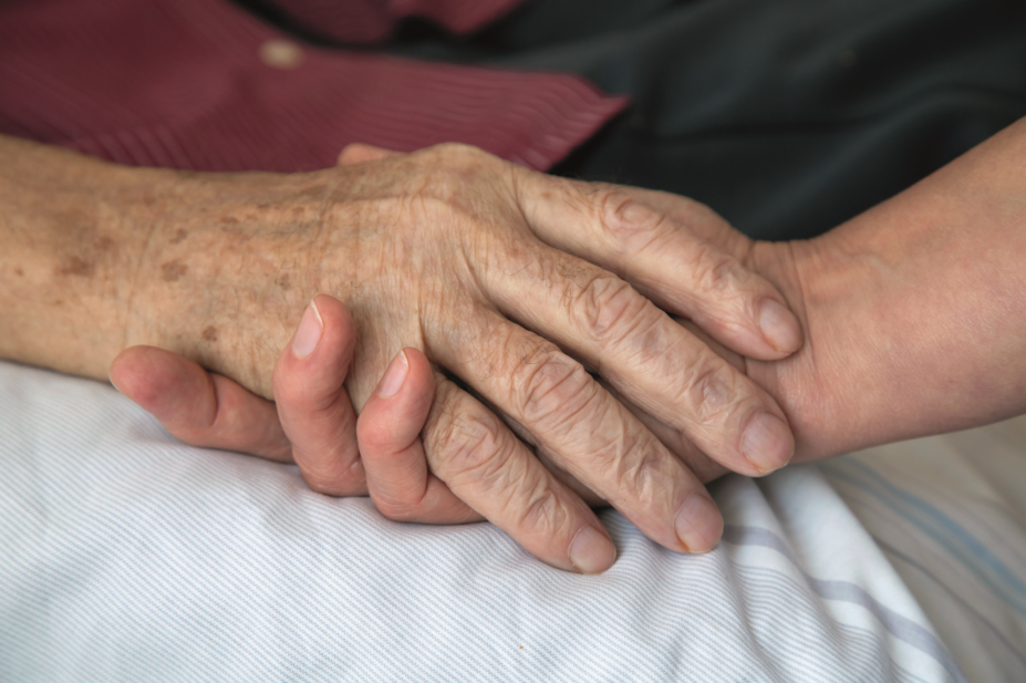 Health worker holding a dying patient's hand