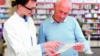 Pharmacist explaining dispensing label to senior male patient