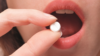 Close up of woman taking ibuprofen tablet