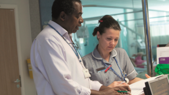 NHS pharmacist discusses patient care with a nurse on a ward