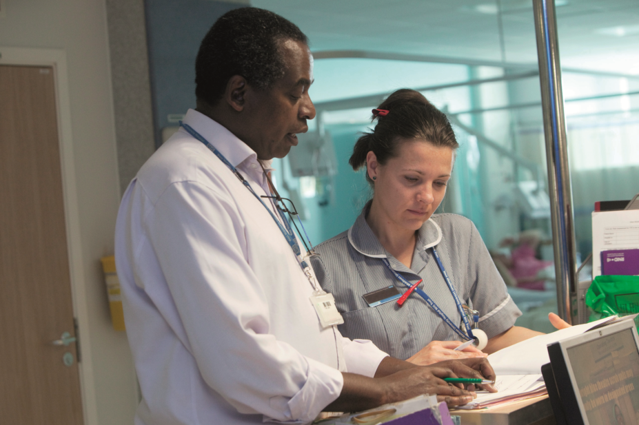 NHS pharmacist discusses patient care with a nurse on a ward