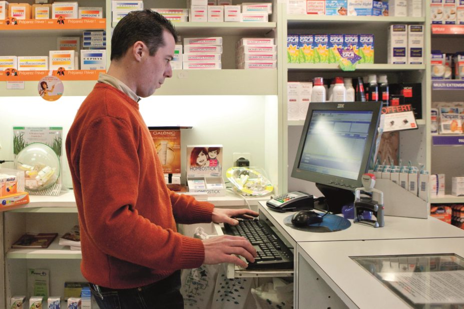 Community pharmacist looking at a patient's information on a pharmacy computer