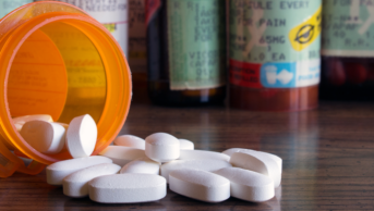 Opioid pills spilling out of pill bottle
