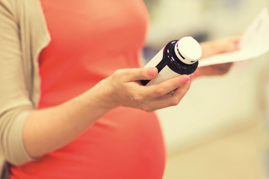 Pregnant woman checks medicine bottle at pharmacy