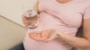 Pregnant woman taking a multivitamin tablet