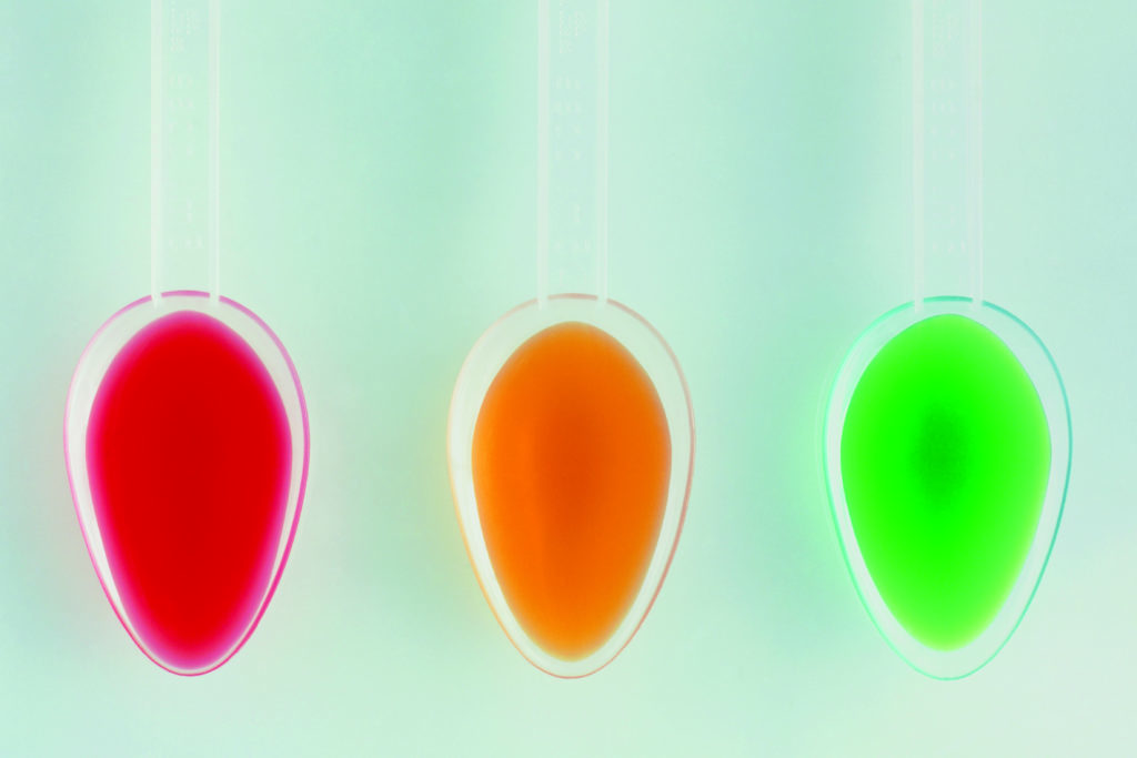 Spoons of red, yellow and green medicine syrup