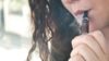 Teenagers who try electronic cigarettes are more likely to go on to try tobacco cigarettes a year later, suggests a study. In the image, close-up of a female teenager smoking an e-cigarette