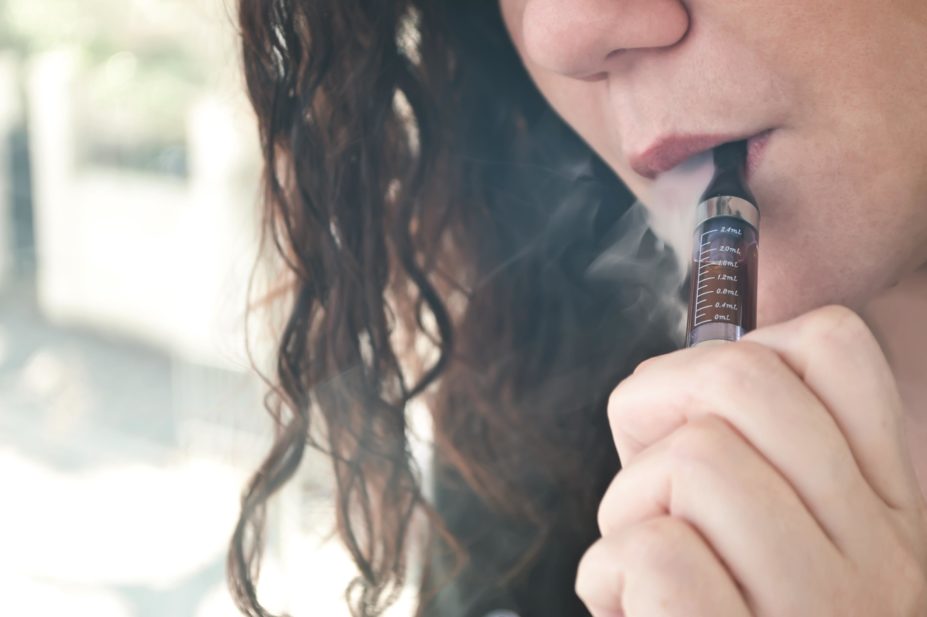 Teenagers who try electronic cigarettes are more likely to go on to try tobacco cigarettes a year later, suggests a study. In the image, close-up of a female teenager smoking an e-cigarette